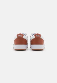 Ein Paar braune und weiße Vans-Sneaker von hinten auf einem weißen Hintergrund, der das Vans-Logo auf der Fersenzunge zeigt.