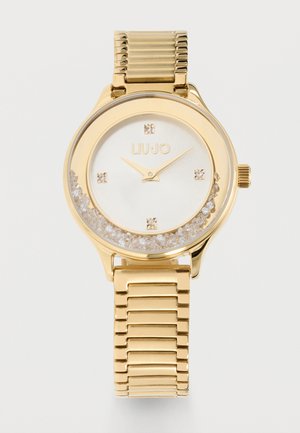 Reloj de pulsera Liu Jo en tono dorado con esfera blanca, marcadores de hora de cristal, cristales flotantes dentro de la esfera y una pulsera elástica de metal.