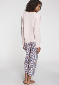 Light pink long-sleeve top paired with blue floral print pants. Soft fabric with a relaxed fit and ankle-length cut.