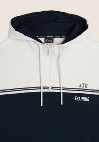 Sweatshirt con cappuccio caratterizzato da una parte superiore bianca e una parte inferiore blu navy, con una zip frontale, un design bicolore e la scritta "TRAINING" in bianco.