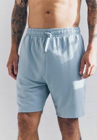 Pantalones cortos de algodón azul claro con cinturilla elástica y cuerda de ajuste. Presentan un corte relajado y una textura suave, adecuados para uso casual.