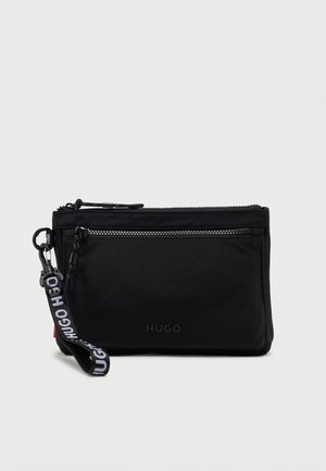Czarny woreczek Hugo z przednią kieszenią na zamek i odłączanym, markowym paskiem na nadgarstek na jednolitym jasnym tle.
