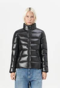 Svart polstret jakke med høy krage, glossy finish, glidelås foran og to lommer foran. Har elastiske mansjetter for en tettsittende passform.
