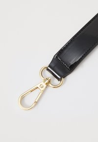 Fekete, fényes pánt lapos kialakítással, arany hardware-rel és klipszes záródással. Simas textúra és látható varrási részletek.