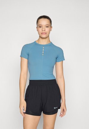 Sinivihreä lyhythihainen paita pyöreällä pääntiellä ja avainaukko-yksityiskohdilla, yhdistettynä mustiin urheilushortseihin, joissa on sivutaskut ja Nike-logo.