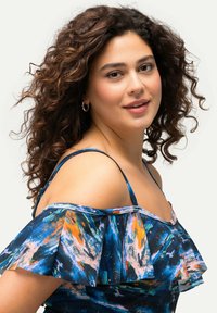 Haut à épaules dénudées bleu et multicolore avec des manches volantes, doté d'un motif abstrait vibrant et d'une texture de tissu douce.