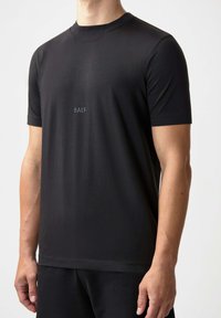Svart kortärmad t-shirt i ett slätt material, med en rundad halsringning och en diskret blå "BALR."-logotyp på bröstet.