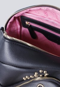 Zwarte leren tas met gouden ritssluiting die gedeeltelijk open is, waardoor de roze stofvoering en een klein ritsvakje aan de binnenkant zichtbaar zijn.