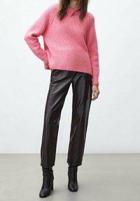 Maglione rosa a coste con scollo rotondo, abbinato a pantaloni neri in pelle a gamba larga e stivaletti neri con tacco. Tessuto e design semplici.