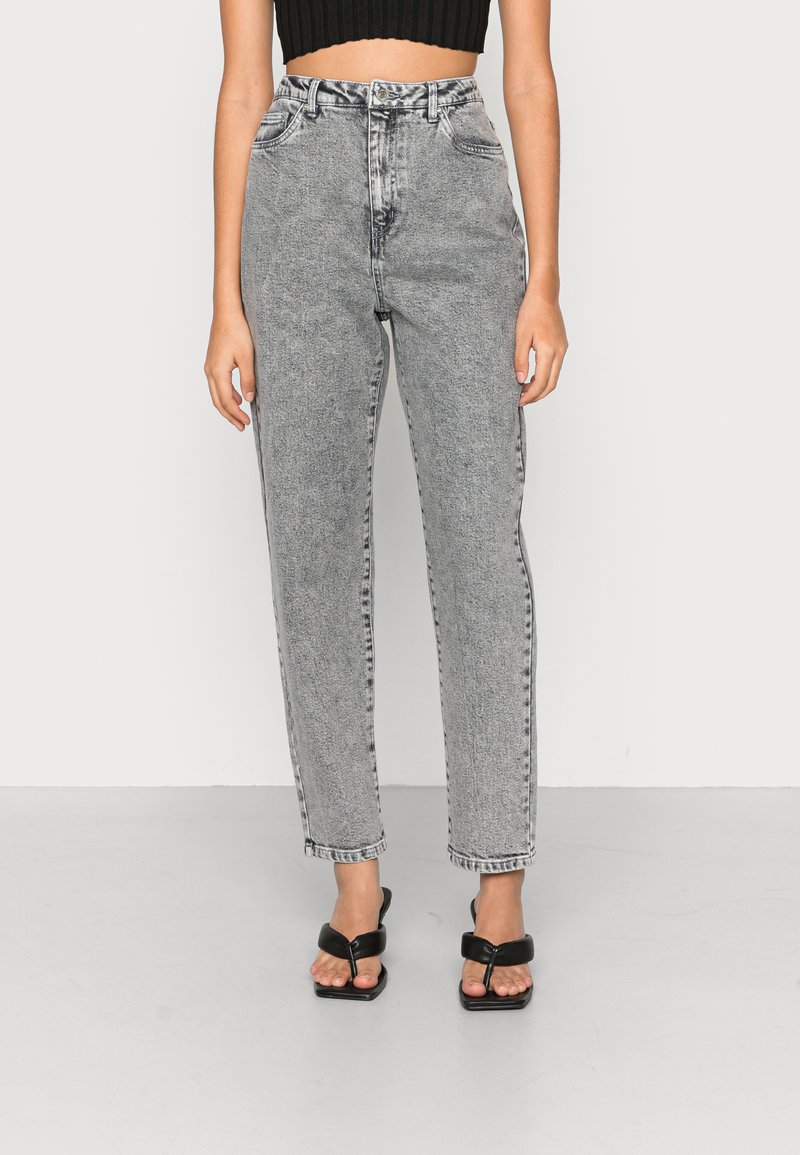 Hochgeschnittene, gerade Jeans aus verblichenem grauem Denim. Verfügt über fünf Taschen und einen Knopfverschluss. Kombiniert mit schwarzen Sandalen.