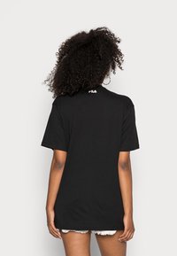 T-shirt noir à manches courtes en coton, avec un col rond et un petit logo blanc à l'arrière. La coupe est décontractée et ample.