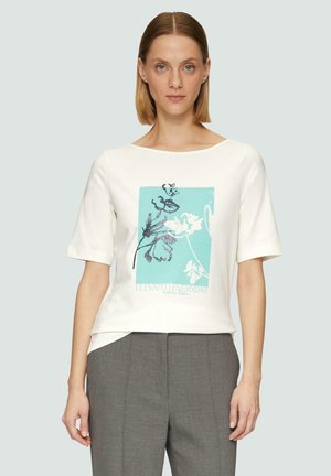 T-shirt en coton blanc à manches courtes, avec un design graphique turquoise comportant des éléments floraux et le texte « ELEVATED EVERYDAY » en bleu.