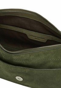 Grüne Wildleder-Handtasche offen, zeigt das Innenfach mit Reißverschluss und Stoffauskleidung sowie einen Metallschnappverschluss auf der vorderen Klappe.