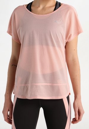 Frau trägt ein lockeres, rosafarbenes Netz-Shirt mit kurzen Ärmeln über einem schwarzen Sport-BH und schwarzen Leggings mit rosafarbenen Seitenteilen.