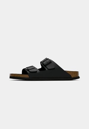 Black slide sandal with two adjustable buckled straps and a brown cork footbed on a white background.