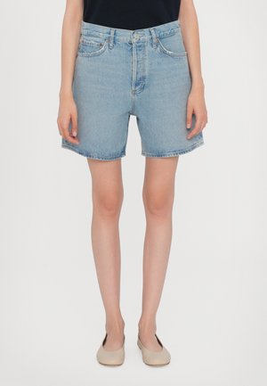 Világoskék farmerrövidnadrág magas derékkal, egyenes szabással és felhajtott szegéllyel. Klasszikus zsebekkel és finom varrással díszítve. Mintázat nélkül.