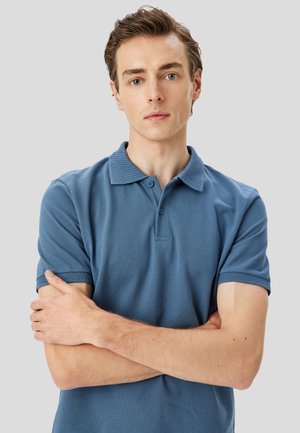 Blaues Polohemd aus weichem Stoff mit geripptem Kragen, Knopfverschluss mit drei Knöpfen und strukturierten Akzenten an den Ärmeln.