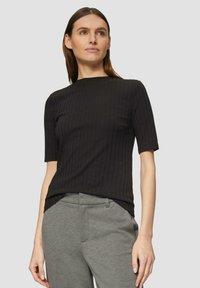 Zwarte geribbelde top met korte mouwen en een ronde halslijn, in combinatie met grijze aansluitende broek. Zachte stoftextuur, ontspannen pasvorm, minimalistisch ontwerp.