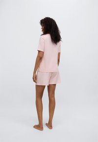 Σετ με ροζ μπλουζάκι κοντομάνικο και σορτς, κατασκευασμένο από απαλό υλικό. Η μπλούζα έχει άνετη γραμμή, ενώ τα σορτς διαθέτουν ελαστική μέση.