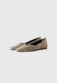 Chaussures plates en daim de couleur taupe, avec un bout pointu et un design crossover unique. Texture douce et style minimaliste sans matériel visible.