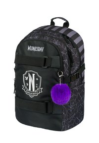 Zaino nero con motivo a ragnatela, ciondolo pom-pom viola e testo "WEDNESDAY". Presenta un logo a scudo e un design a righe nella parte superiore.