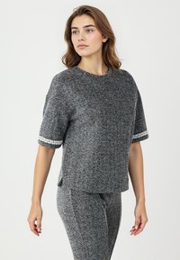 Grijze getextureerde korte mouw sweater met contrasterende decoratieve rand aan de manchetten. Heeft een ronde halslijn en zijsplitten voor gemakkelijke draagbaarheid.