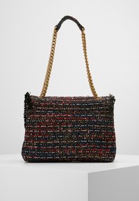 Obdélníková kabelka z tweedu s červenými, modrými a hnědými nitěmi, černými třásněmi na okraji a zlatým řetízkem s černým koženým ramenním polstrováním.
