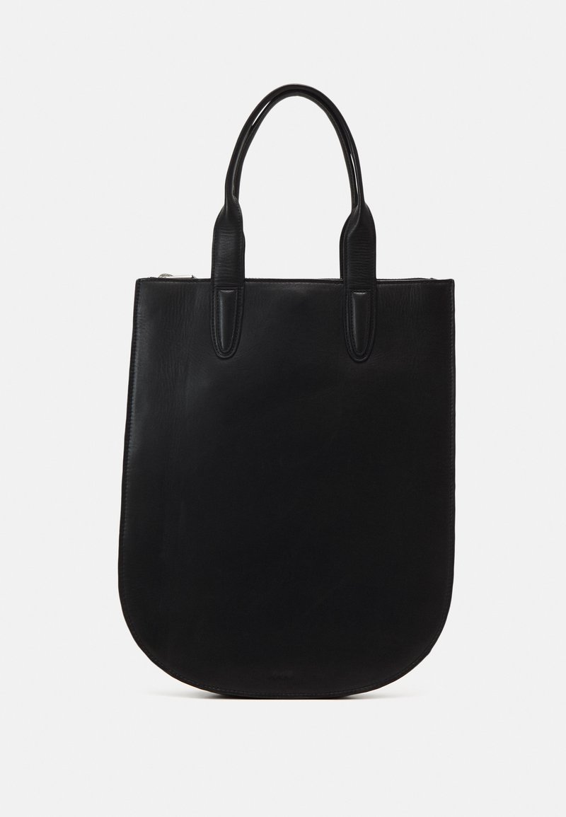 Sac cabas en cuir noir avec des bords inférieurs arrondis, deux poignées et une fermeture éclair en haut, présenté sur fond blanc.