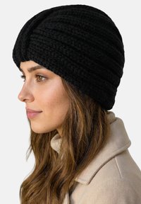 Sort strikket hue med ribstrikket mønster og en snoet detalje foran. Blød tekstur, tæt pasform, designet til at dække ørerne.
