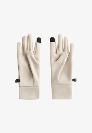 Svetlo bež rokavice z gladko teksturo, z črnimi konicami prstov in nastavljivimi paščki na zapestju za varno prileganje.