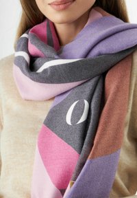 Écharpe multicolore avec des motifs géométriques en gris, rose, lavande et marron, fabriquée en tissu doux, drapée autour du cou.