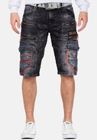 Zwarte denim cargoshorts met meerdere ritszakken, rode accenten en een relaxte pasvorm. Gestructureerde stof met contrasterende stikseldetails.