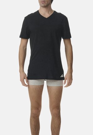 Schwarzes V-Ausschnitt-T-Shirt aus weichem Material mit kurzen Ärmeln, ergänzt durch graue Shorts. Verfügt über ein kleines weißes Logo in der Nähe des Saums.