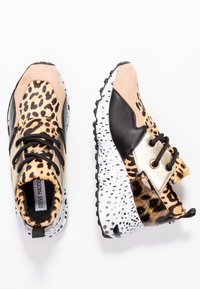 Baskets épaisses avec imprimé léopard, suède beige, cuir noir, accents métalliques dorés, lacets noirs et semelles blanches mouchetées.