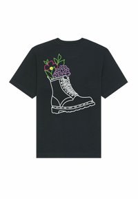 Zwart T-shirt met een witte omranding van een laars, gevuld met kleurrijke bloemen, waarbij paarse en rode bloemblaadjes op de donkere stof opvallen.