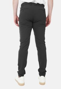 Pantaloni neri con una vestibilità su misura, dotati di tasche posteriori e una cintura. Abbinati a sneakers bianche per un contrasto.