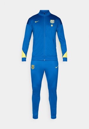 Chándal azul de Nike con detalles amarillos, que incluye una chaqueta con cremallera y pantalones ajustados a juego. Lleva el logo del equipo en el pecho y el muslo.