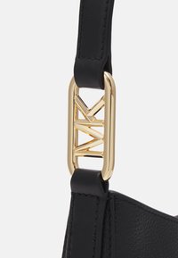 Sort læderhåndtaske rem med en guldfarvet metalspænde med geometrisk design. Glat tekstur med synlige sy-detaljer.