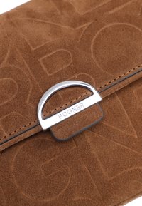 Clutch in suede marrone con motivo a logo impresso, dotato di una chiusura in metallo argentato. Texture liscia, forma rettangolare e cuciture pulite.