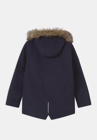 Parka in blu navy invernale con maniche lunghe e cappuccio rifinito in pelliccia sintetica marrone, mostrata sul retro su uno sfondo bianco.
