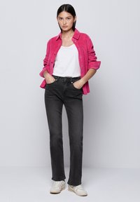 Fuchsia corduroy overhemd, witte tanktop, zwarte rechte jeans en lichte sneakers. Soepele texturen en casual ontwerp met metalen knopen.