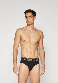 Férfi fekete alsónadrág arany mintás derékszalaggal. Az anyag simának és testre szabottnak tűnik, klasszikus szabású, a kényelemre helyezve a hangsúlyt.