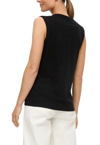 Black sleeveless top with a round neckline, made from soft fabric, features a slightly loose fit and minimal stitching detail at the shoulders.