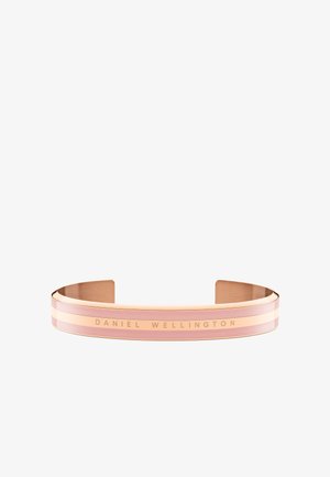 Náramok z ružového zlata s dvoma horizontálnymi ružovými pruhmi. Vrytý nápis "DANIEL WELLINGTON" na hladkom, kovovom povrchu. Elegantný, minimalistický dizajn.