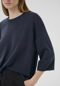 Navyblaues Sweatshirt aus strukturiertem Material, mit weitem Rundhalsausschnitt und dreiviertellangen Ärmeln mit gerippten Bündchen.
