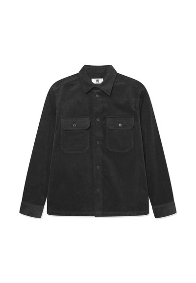 Chemise noire en velours côtelé à manches longues, avec col, fermeture boutonnée sur le devant et deux poches poitrine boutonnées, posée à plat sur fond blanc.