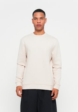 Lys beige crewneck sweatshirt i myk stoff, med lange ermer og smal ribbestrikket kant. Liten logo på venstre bryst.