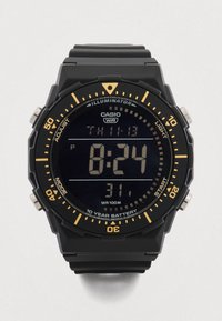 Cyfrowy zegarek z czarnym paskiem z gumy i czarną, teksturowaną kopertą. Posiada duży wyświetlacz LCD z białymi cyframi i pomarańczowymi akcentami. Wodoodporny.