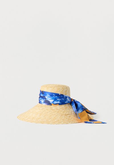 Chapeau de paille à large bord avec un foulard bleu à fleurs noué autour de la calotte, tombant sur un côté.