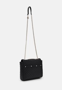 Sort quiltet håndtaske med en sølvfarvet kæderem, der har en lædertophank og metalaccenter foran for ekstra detalje.